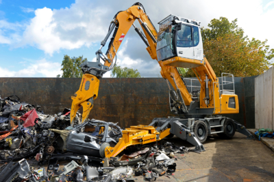 Bagger zerlegt Auto auf Schrottplatz